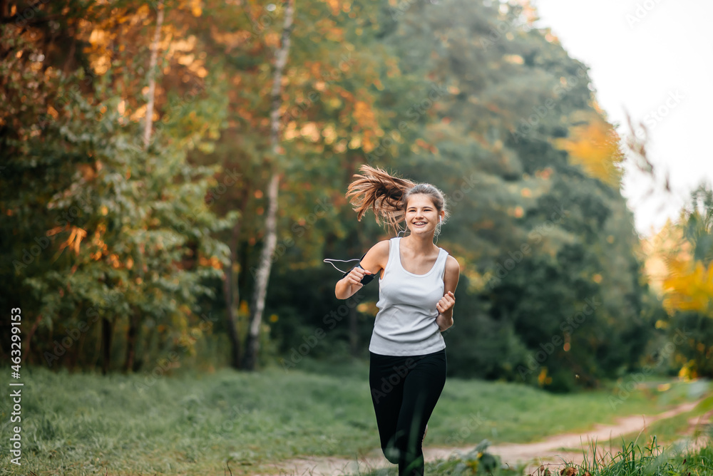 Woman running in autumn fall forest. Healthy lifestyle . Fit ethnic Caucasian fitness model.