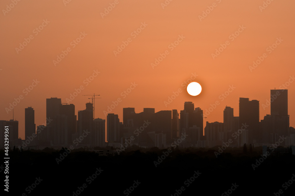 front view, far distance of tropical sun, rising over silhouetted, Miami skyline