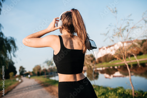 A girl in headphones is engaged in outdoor fitness in a metropolis. running and sports in summer