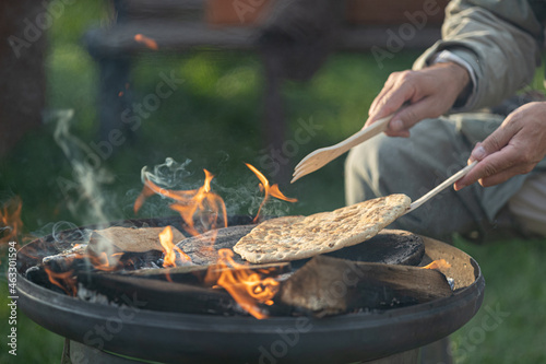 farmer bakes bread outdoors, cooking on open fire photo