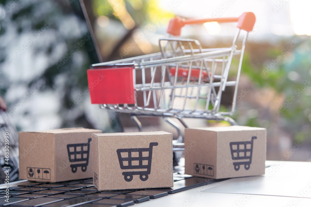 Shopping online - Parcel or Paper cartons with a shopping cart logo in a trolley on a laptop keyboard. Shopping service on The online web. offers home delivery.