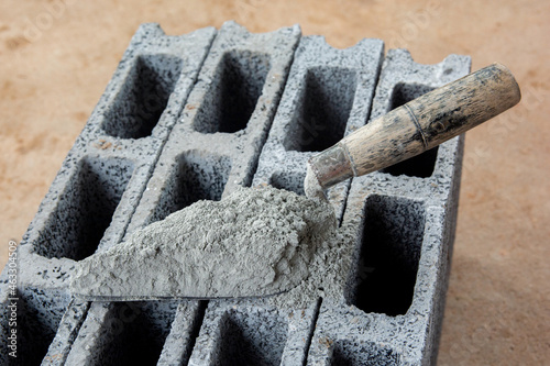 Cement powder or mortar with  trowel put on the Concrete brick for construction work..