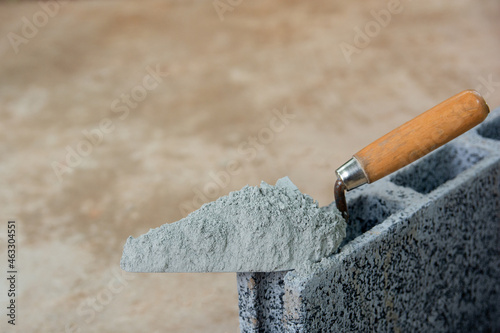 Cement powder or mortar with  trowel put on the Concrete brick for construction work..