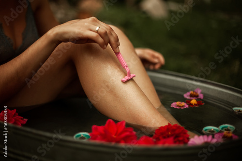 girl in the bathroom with flowers on the street shaves her legs