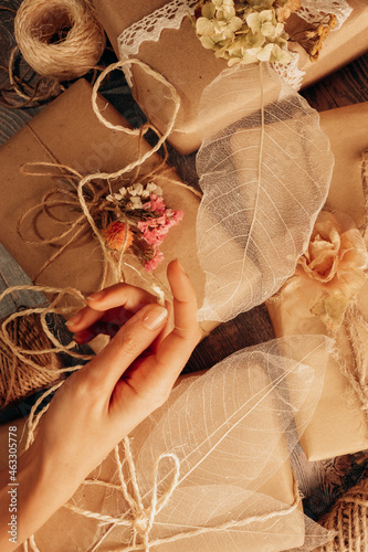 Florist wrapping present boxes of ecological materials with woman hand in rustic spring style. Top view