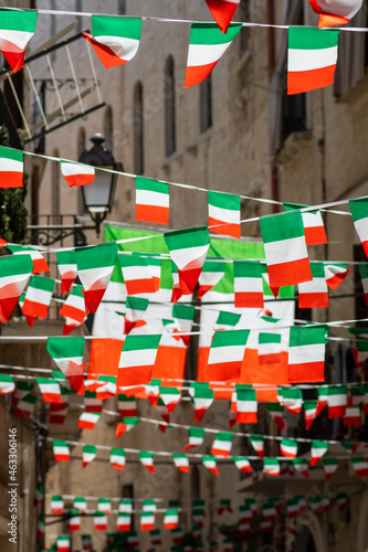 Italian flags and pennants waving in an old town narrow street of a city in Italy, vertical photo