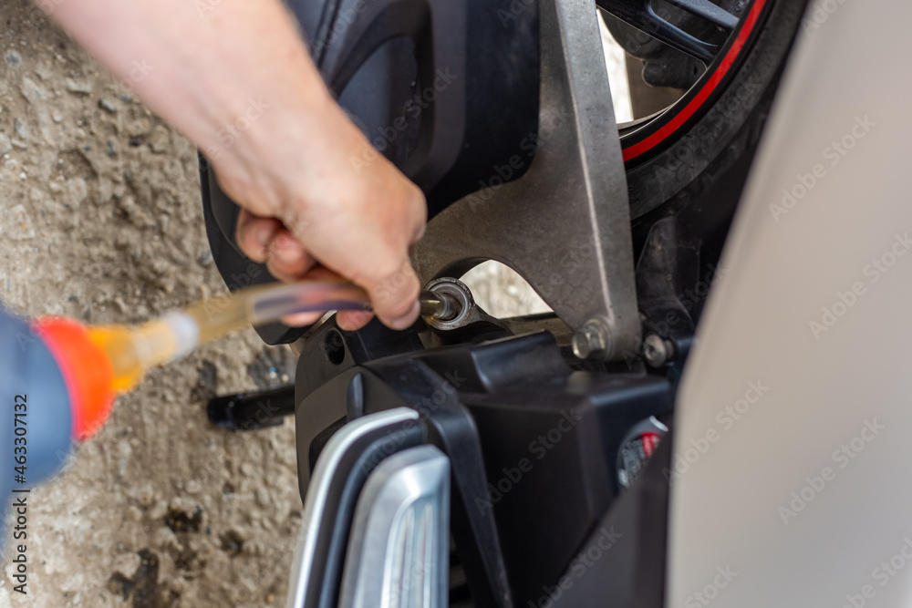 A car mechanic pours engine oil into a motorbike engine. Repair and maintenance of motorcycles