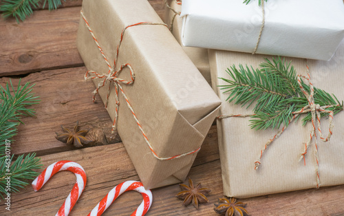 Christmas gifts or gift box wrapped in kraft paper with decorations, pine cones and fir branches on a rustic wooden background photo