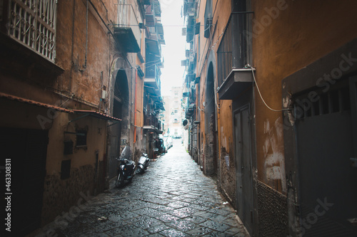 Scenic view of typical narrow alleyway lined with scooters and laundry lines in the Medieval Centro Storico of Naples, Italy