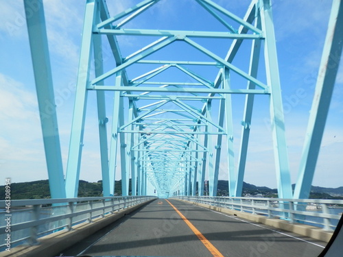 青空のような真っ青に塗装されたトラス橋を通る風景