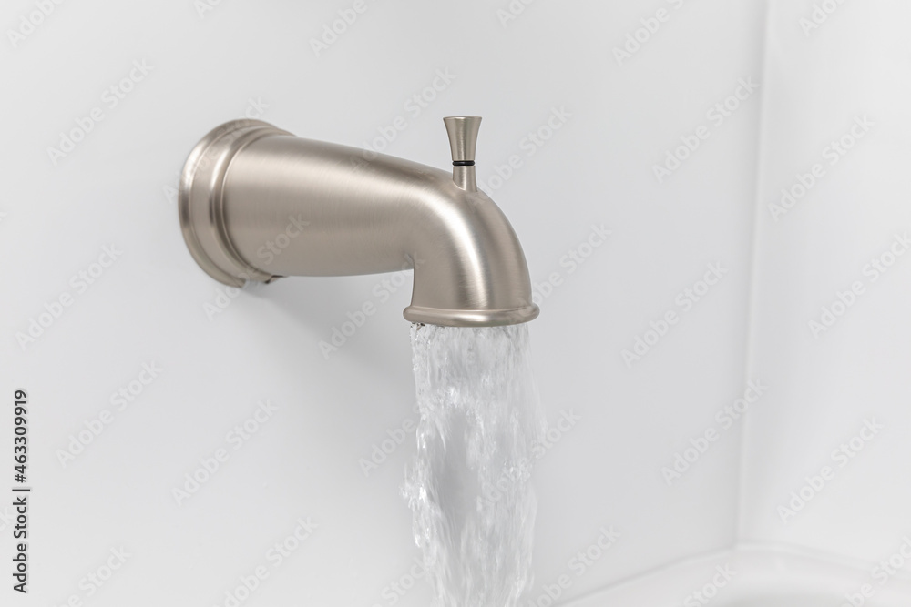 Bathtub spout flowing water. Plumbing repair, bathroom remodel and renovation concept Bathtub spout flowing water. Plumbing repair, bathroom remodel and renovation concept