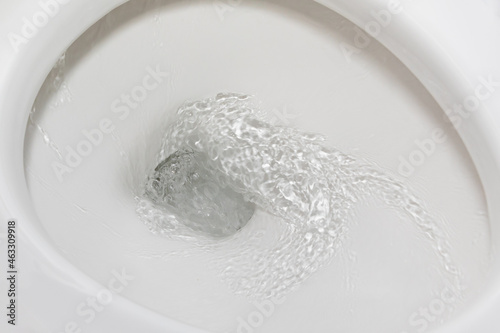 Motion blur of flushing water in toilet bowl. Plumbing, home repair and water conservation concept.