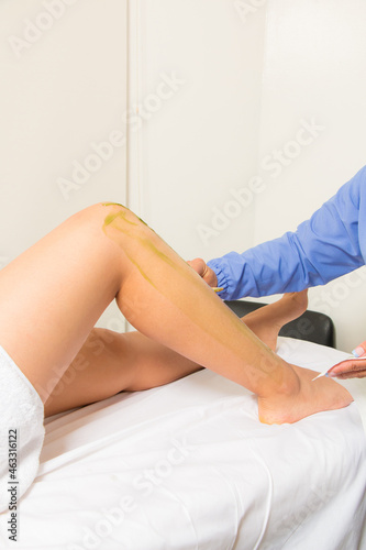 Waxing your legs: waxing procedure. Hairless legs, personal care. woman at the spa getting a body treatment