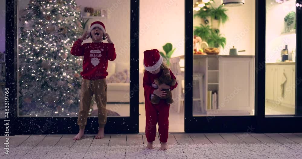 amazed baby girl stepping into the first snow falling on patio at Christmas night, cozy family atmosphere at home