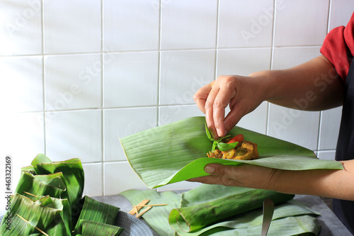 ASian Woman Cooking in the Kitchen, Step by Step Making Pepes (Steam Side Dish) from Indonesia. Add Lemon Basil Before Wrapping pepes with Banana Leaf photo