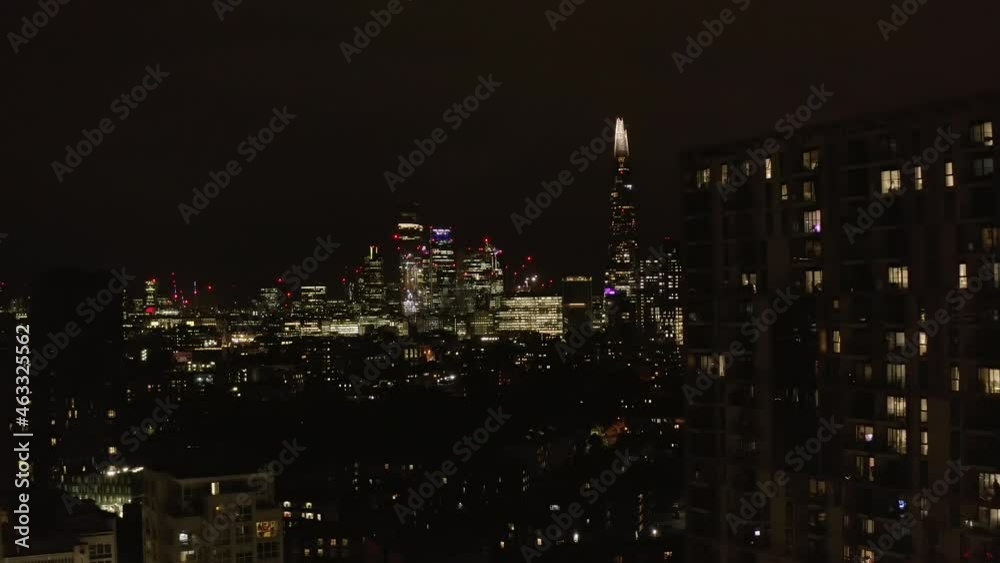 Forwards fly above urban neighbourhood at night. Revealing view of glowing downtown skyscrapers. London, UK Forwards fly above urban neighbourhood at night. Revealing view of glowing downtown skyscrapers. London, UK
