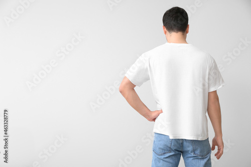 Handsome young man in stylish t-shirt on light background, back view