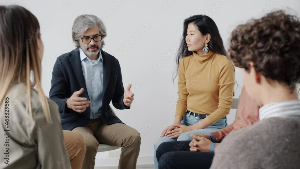 Therapist is speaking to patients during group session holding hands giving help and support while people with closed eyes are listening Therapist is speaking to patients during group session holding hands giving help and support while people with closed eyes are listening