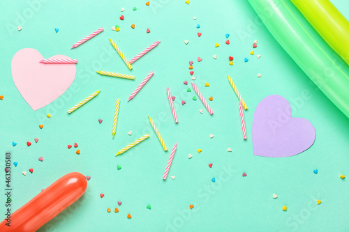 Birthday candles with confetti and balloons on color background