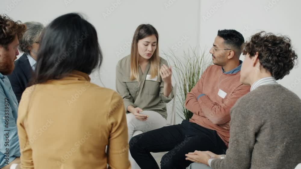 Unhappy woman is sharing problems and crying during group therapy session while people are holding hands expressing support. Emotions and psychology concept. Unhappy woman is sharing problems and crying during group therapy session while people are holding hands expressing support. Emotions and psychology concept.