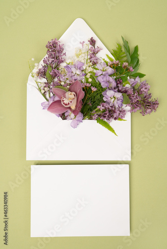 Stationery flat lay with blank card and envelope with fresh purple lilac and orchid flowers photo