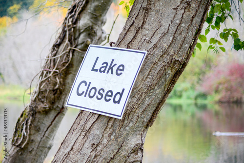 Lake closed sign posted on a tree at the lake