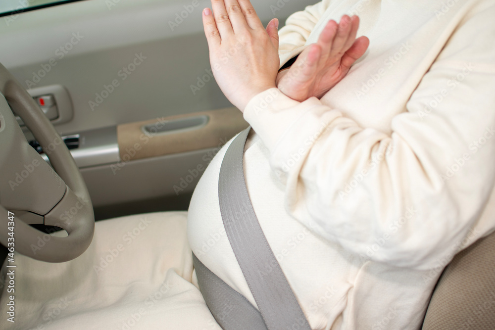 A young pregnant Asian woman wears a seatbelt inappropriately and shows no mark A young pregnant Asian woman wears a seatbelt inappropriately and shows no mark