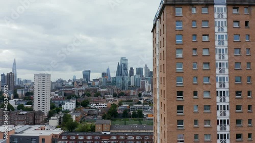 Descending footage of Winterton House. High rise apartment building with brick facade. Modern tall office buildings in background. London, UK photo