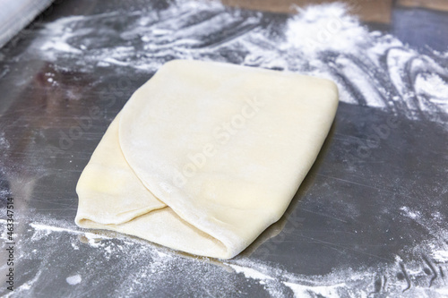 Rolled out puff pastry on a table with flour. Workpiece for pastry
