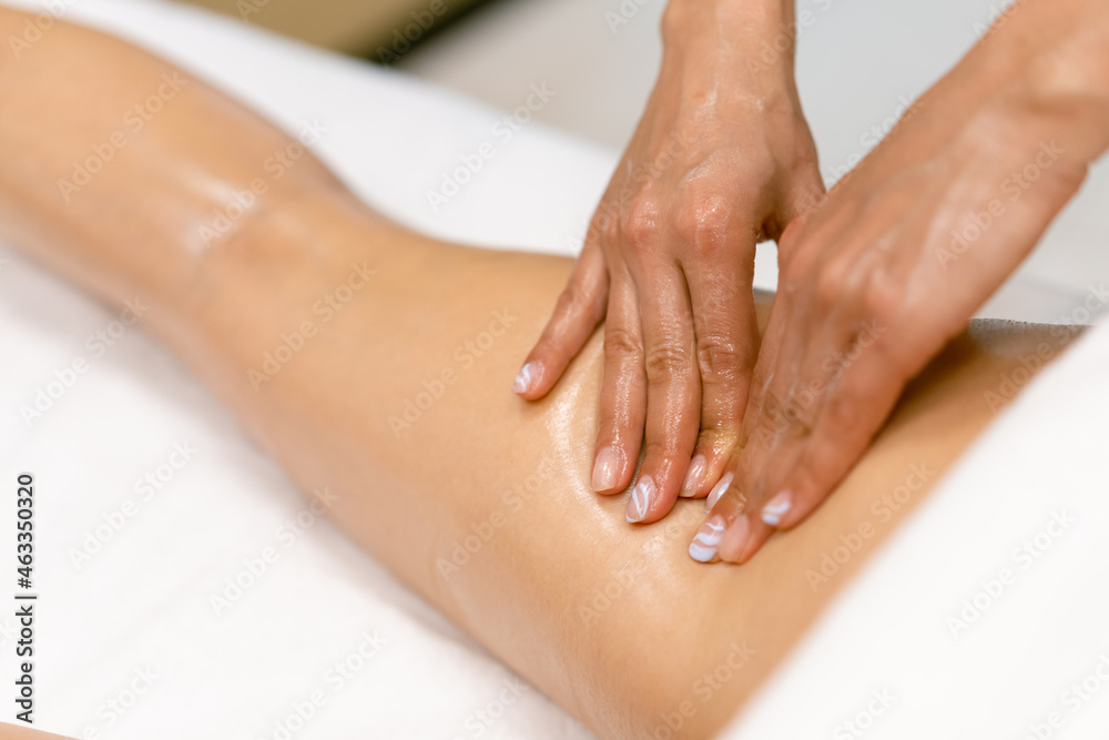 Beauty salon professional pouring oil from a massage candle on the back of his patient. Beauty salon professional pouring oil from a massage candle on the back of his patient.