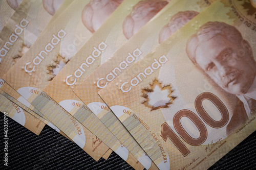 Multiple 100 Canadian dollar bills on the table. Counting cash on the table. Emptying wallet for purchases. Canadian currency and counting bills for payment or saving for the future. Large cash value