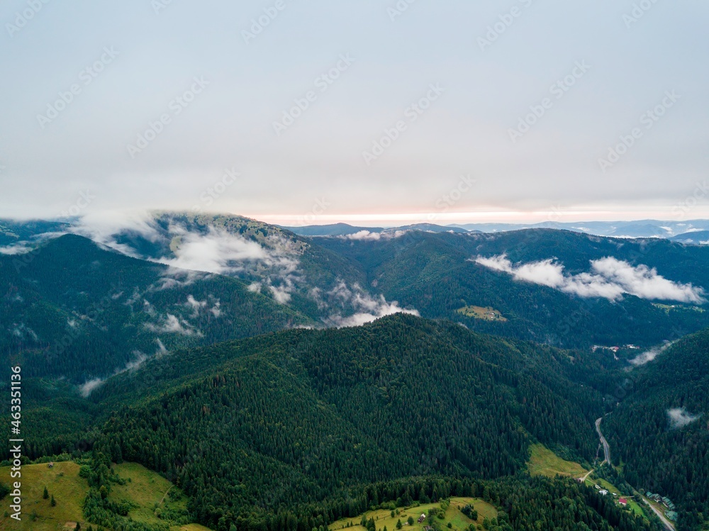 High flight among the clouds at dawn. Ukrainian Carpathians in the morning in the haze. Aerial drone view.