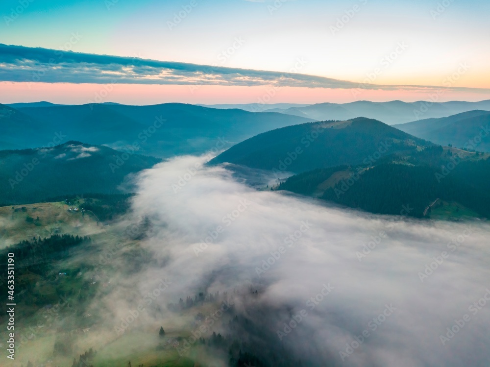 Fog in the mountain valley at dawn. Ukrainian Carpathians in the morning in the haze. Aerial drone view.