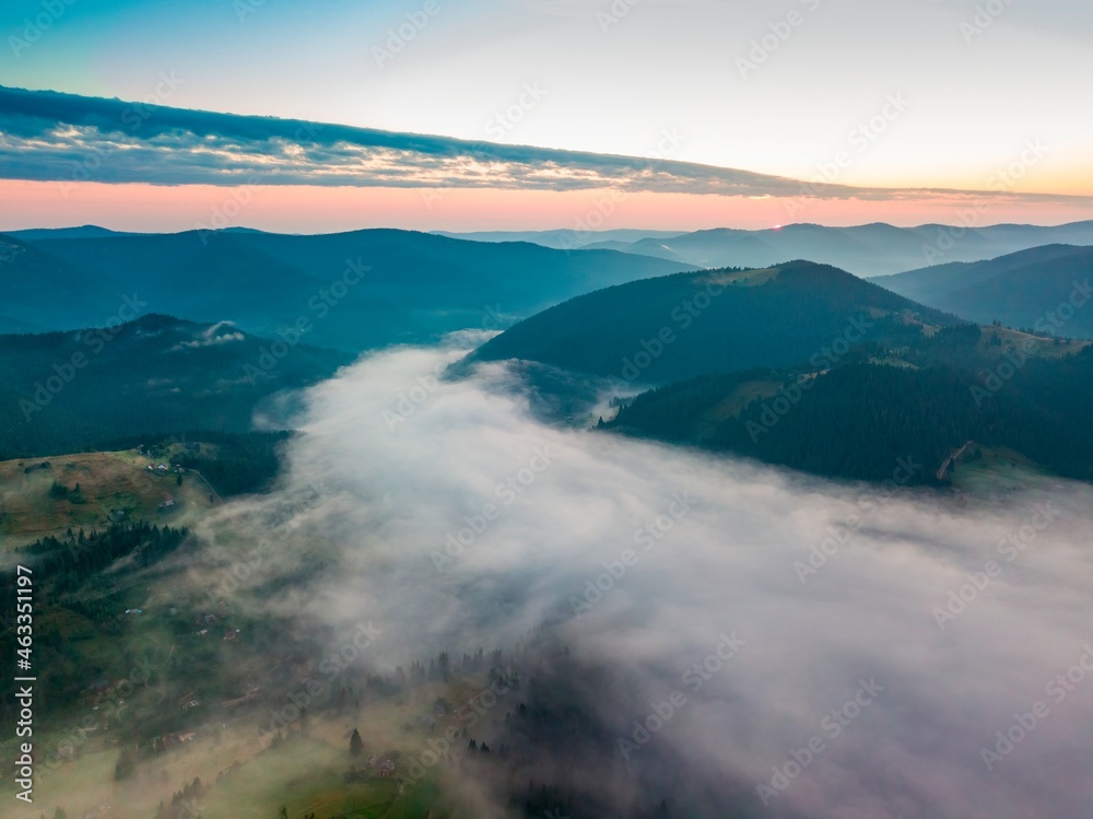 Fog in the mountain valley at dawn. Ukrainian Carpathians in the morning in the haze. Aerial drone view.