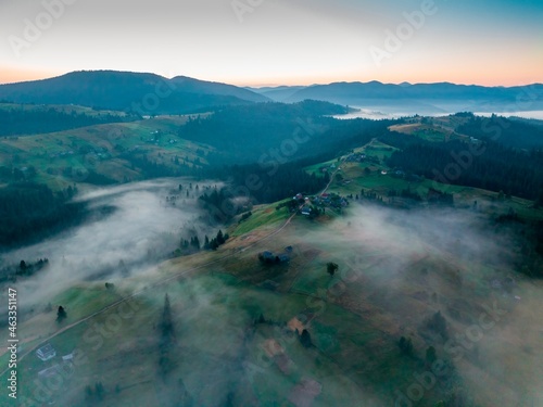 Fog in the mountain valley at dawn. Ukrainian Carpathians in the morning in the haze. Aerial drone view.