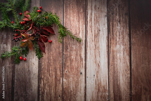 christmas decoration on wooden background with acorn, rose hips and red leaves