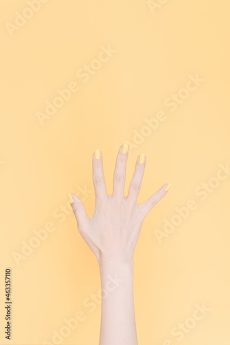 hand showing number five In front of the yellow background,