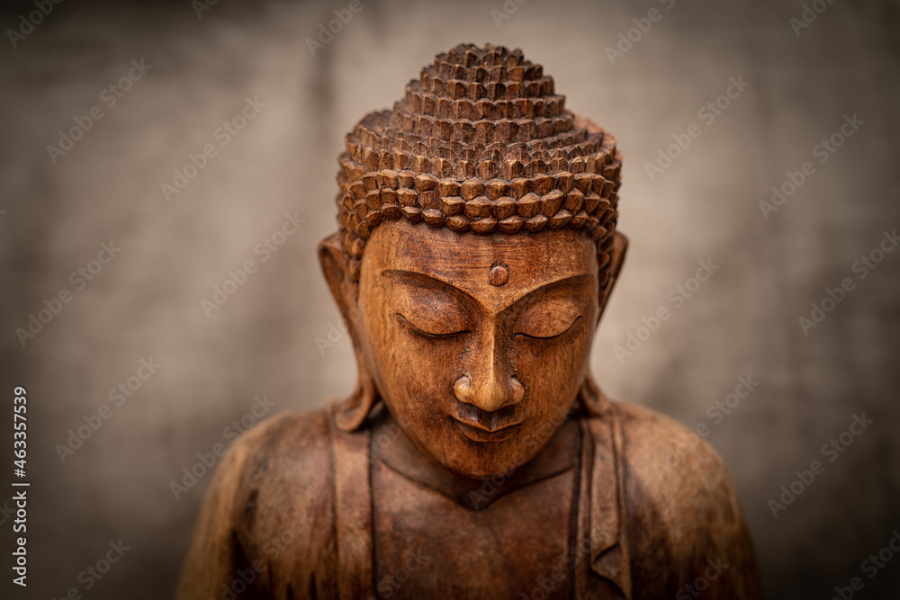 wooden buddha on grey background