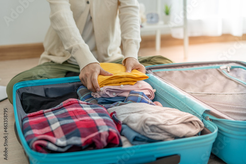 Travel bags for vacation trips. A young woman prepares clothes and personal items to put in her suitcase. Pack your bags before traveling