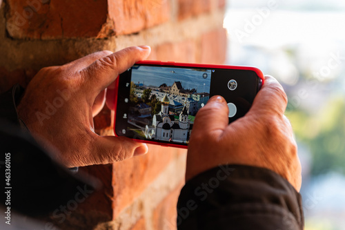The hands of an elderly man holding a phone and photographing a panorama in Nizhny Novgorod, Russia, tourism,