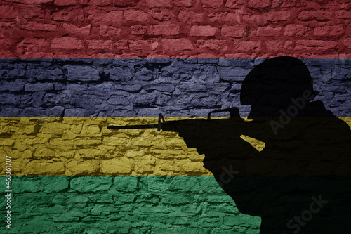 Soldier silhouette on the old brick wall with flag of mauritius country.