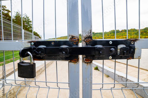 Close-up of a Padlock On a rusty Fence made of mesh, against a background of trees