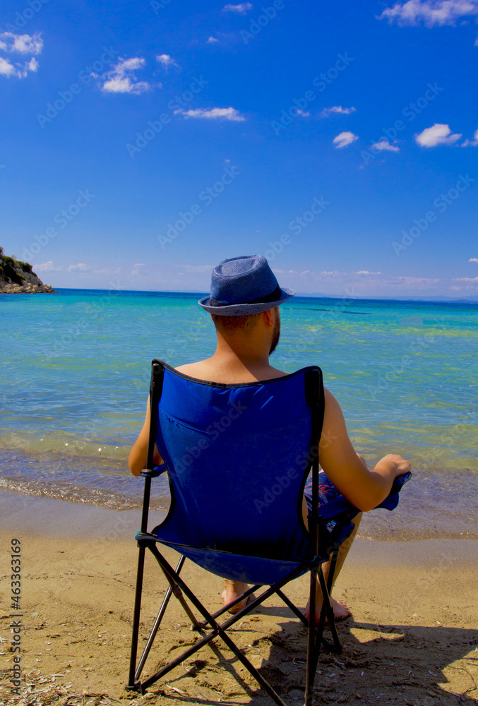handsome man in a blue hat resting on the beach