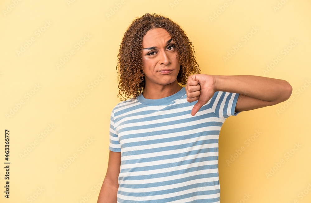 Young latin transsexual woman isolated on yellow background showing thumb down, disappointment concept. Young latin transsexual woman isolated on yellow background showing thumb down, disappointment concept.