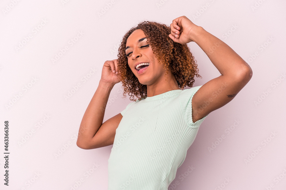 Young latin transsexual woman isolated on pink background celebrating a special day, jumps and raise arms with energy. Young latin transsexual woman isolated on pink background celebrating a special day, jumps and raise arms with energy.
