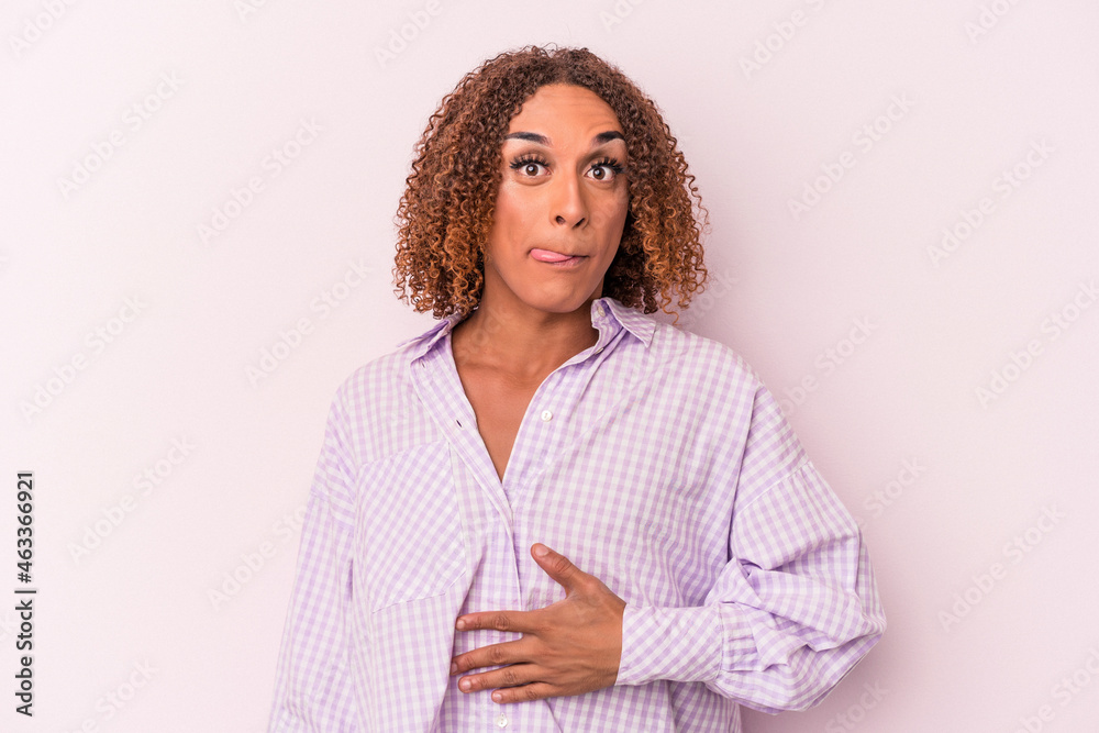 Young latin transsexual woman isolated on pink background touches tummy, smiles gently, eating and satisfaction concept. Young latin transsexual woman isolated on pink background touches tummy, smiles gently, eating and satisfaction concept.