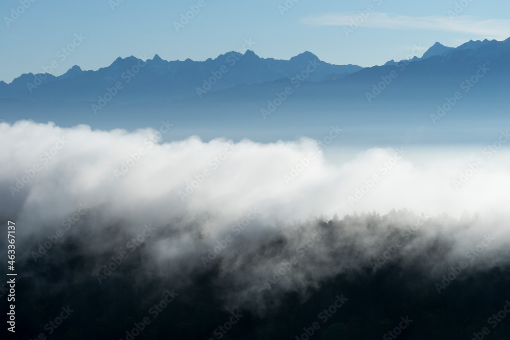 Layers of clouds and forest with mountains in the background