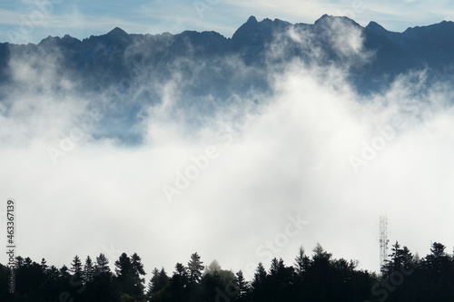Layers of clouds and forest with mountains in the background