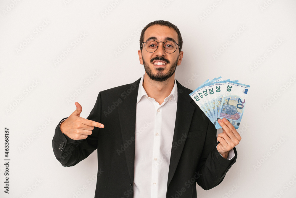 Young caucasian business man holding banknotes isolated on white background person pointing by hand to a shirt copy space, proud and confident Young caucasian business man holding banknotes isolated on white background person pointing by hand to a shirt copy space, proud and confident