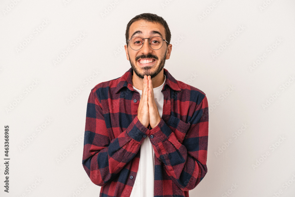 Young caucasian man isolated on white background holding hands in pray near mouth, feels confident. Young caucasian man isolated on white background holding hands in pray near mouth, feels confident.